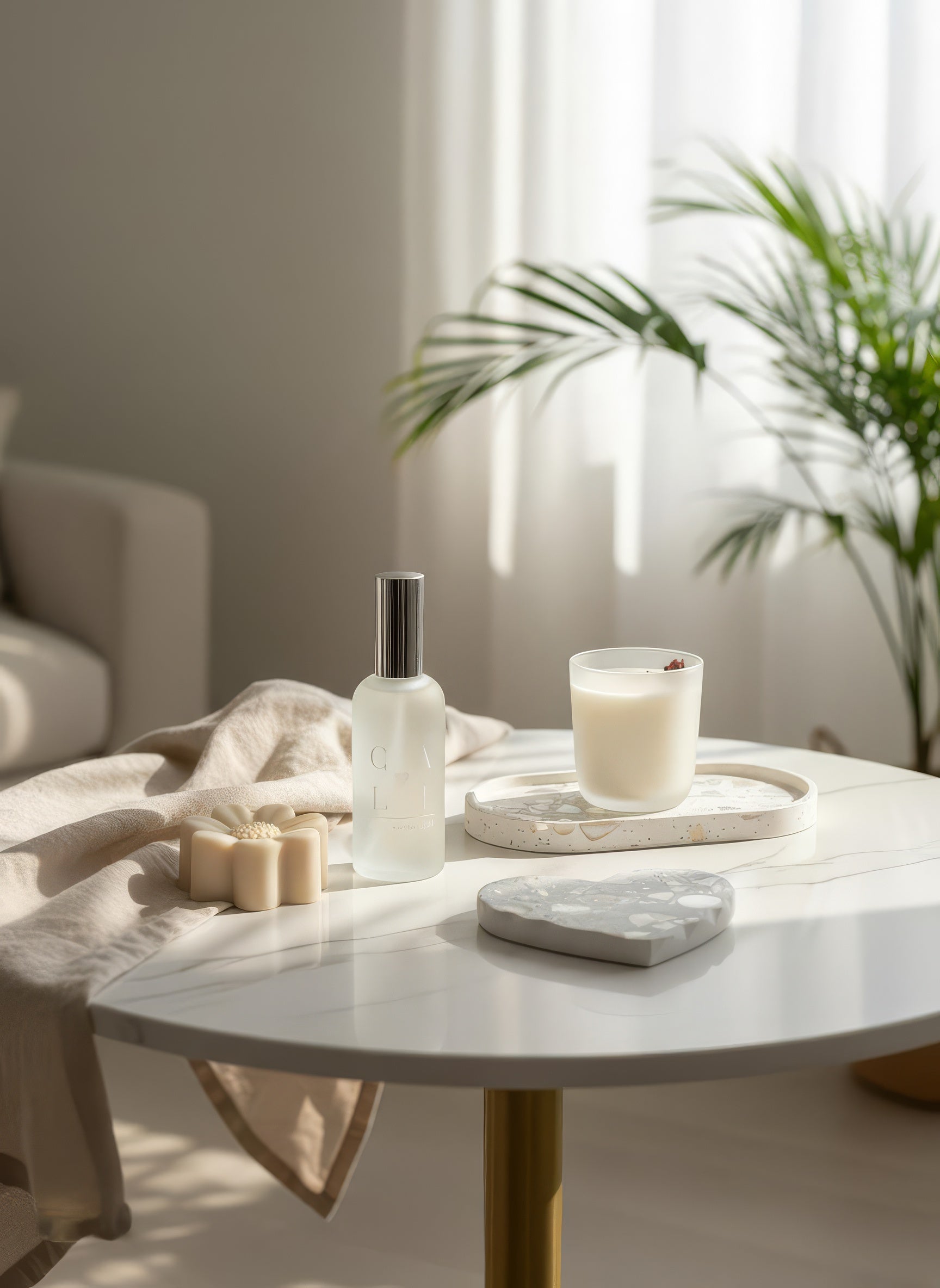 Table with a candle, spray bottle, and on decorative seashell decor in a bright room with plants