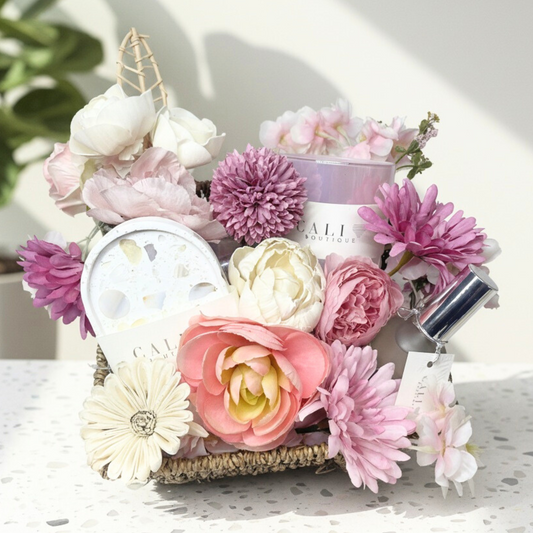 Decorative floral gift basket with products on a light surface
