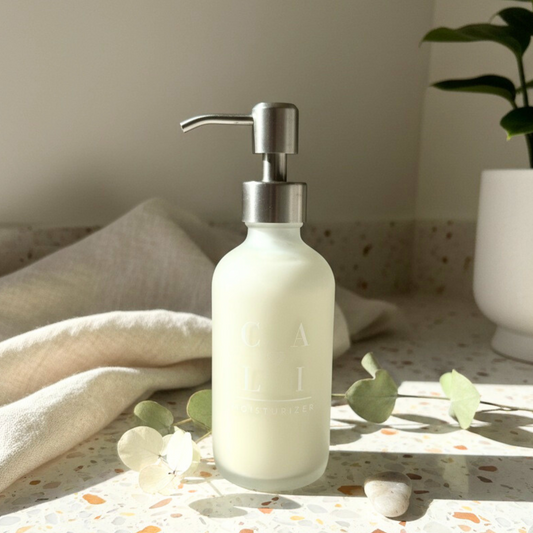 frosted white lotion dispenser with silver pump on a surface with a neutral background