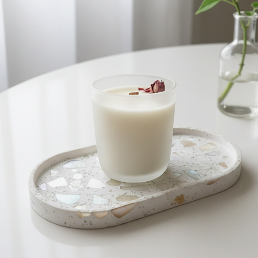 white frosted glass wooden wick candle with a pink rose on a decorative tray with a blurred background