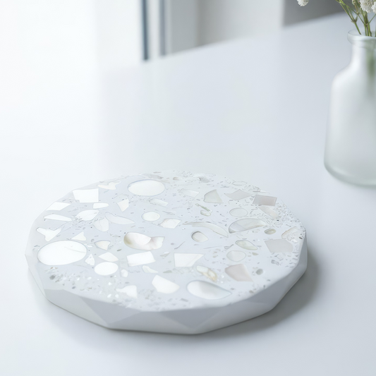White terrazzo-style round coaseter on a light surface with a vase in the background