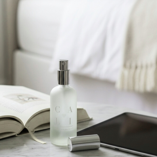 frosted spray bottle labeled Cali Love Aromatherapy on a marble surface with a blurred background