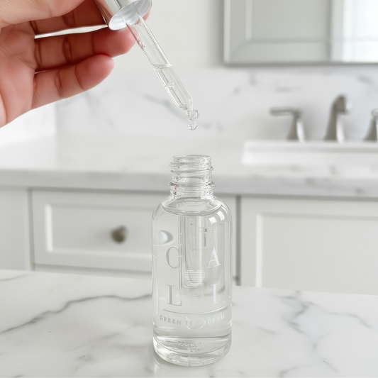 Clear dropper bottle with a dropper being used on a marble surface.