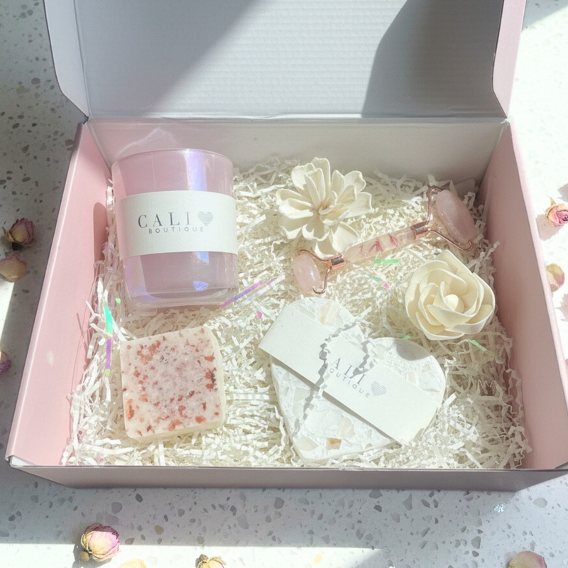Gift box with a candle, soap, and decorative flowers on a light background