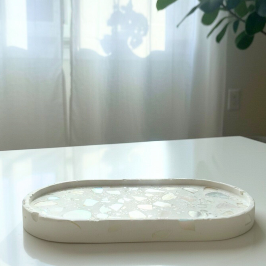 White decorative tray with shell inlay on a white surface with a blurred background