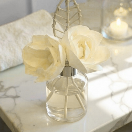 Clear glass reed diffuser with wooden flowers on a marble surface