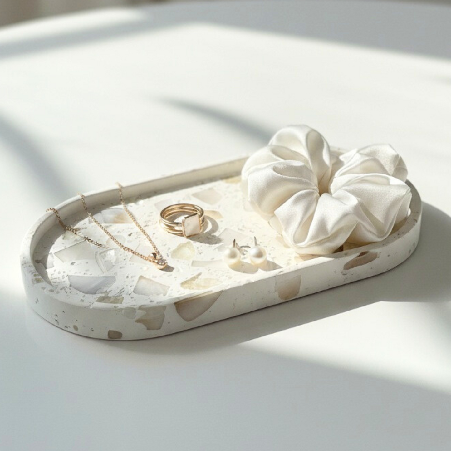 Jewelry tray with necklaces, rings, and a scrunchie on a light surface.