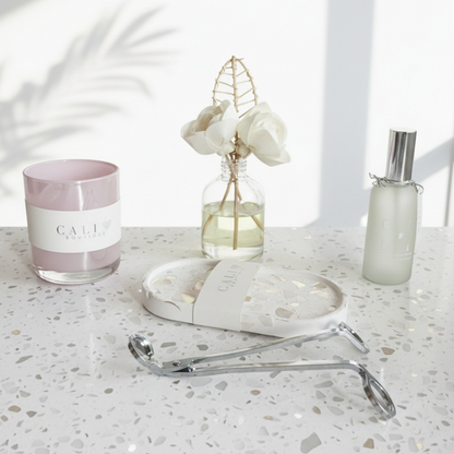 Candle, reed diffuser, mood mist, trinket tray and wick trimmer on a light surface