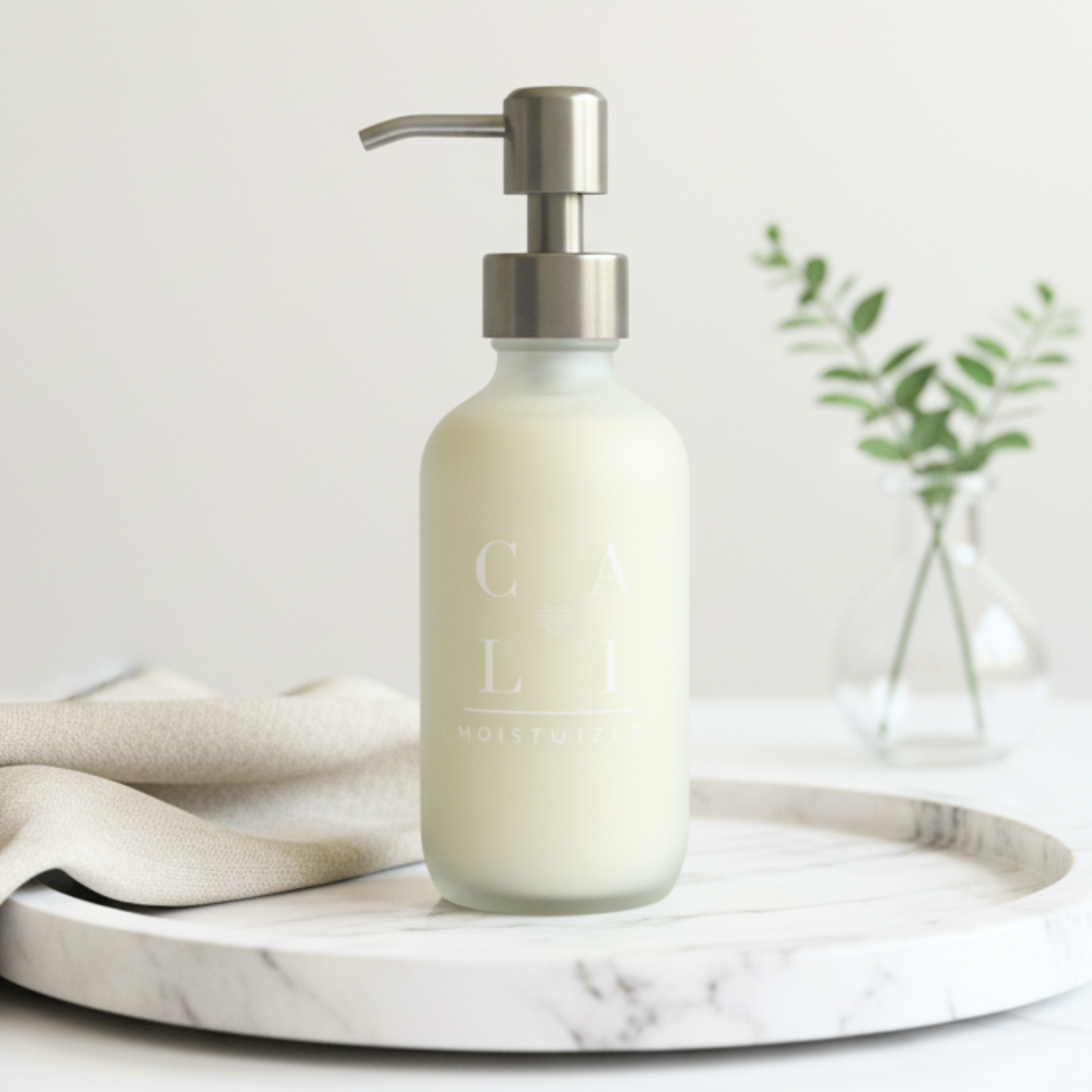 Bottle of lotion with silver pump on a marble tray surface, blurred background