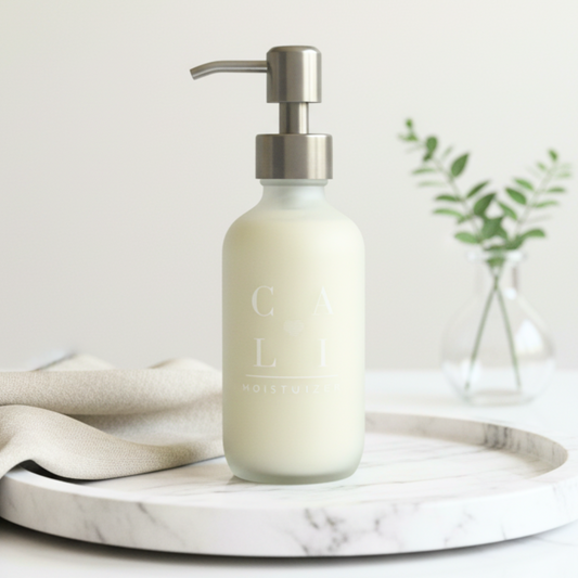 Bottle of lotion with silver pump on a marble tray surface, blurred background