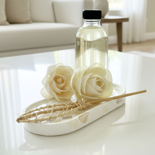 reed diffuser refill of bottle and wooden flowers sitting on a luminous handmade trinket tray made with natural shells and stones