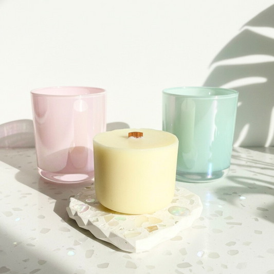 two iridescent glasses with a candle refill on a heart shaped shell and stone coaster.