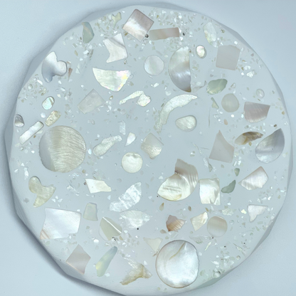 Round decorative item with shell on a light gray background