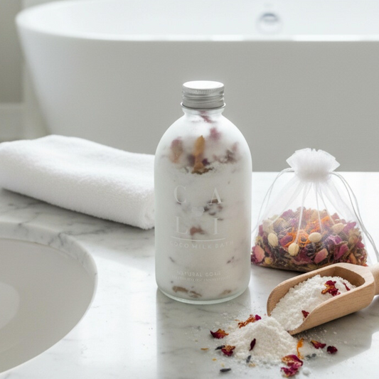 Bottle of bathmilk with a scoop and bag and bag of dried flowers on a bathroom counter