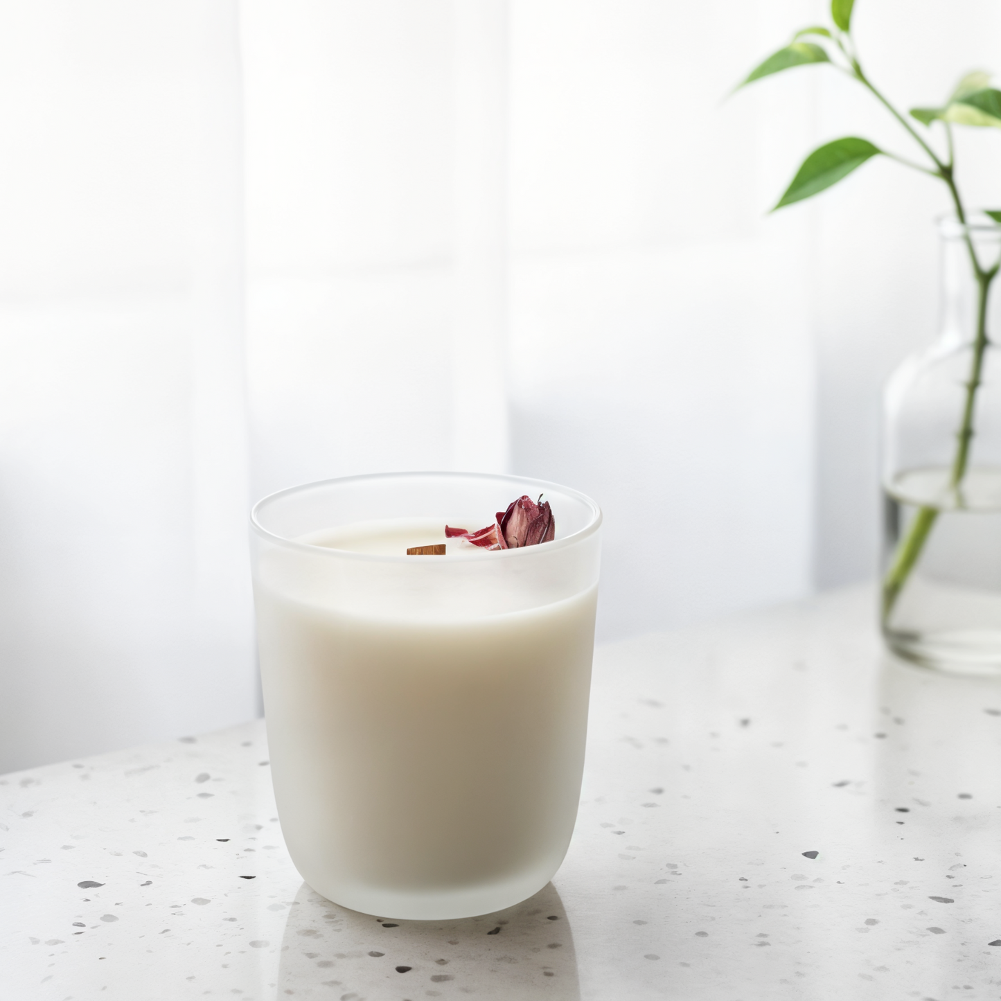 cali dream candle in a white frosted glass with a pink rose on top with a light blurred background
