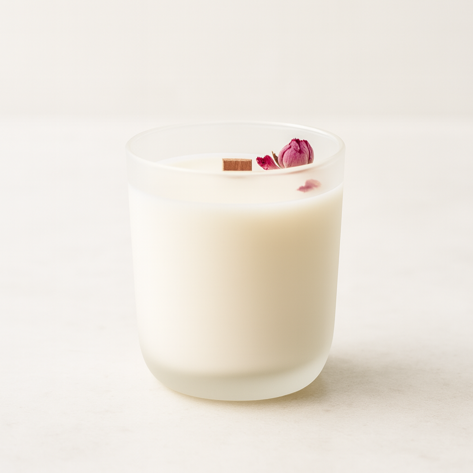 white frosted glass wit ha wooden wick and pink rose in a white background